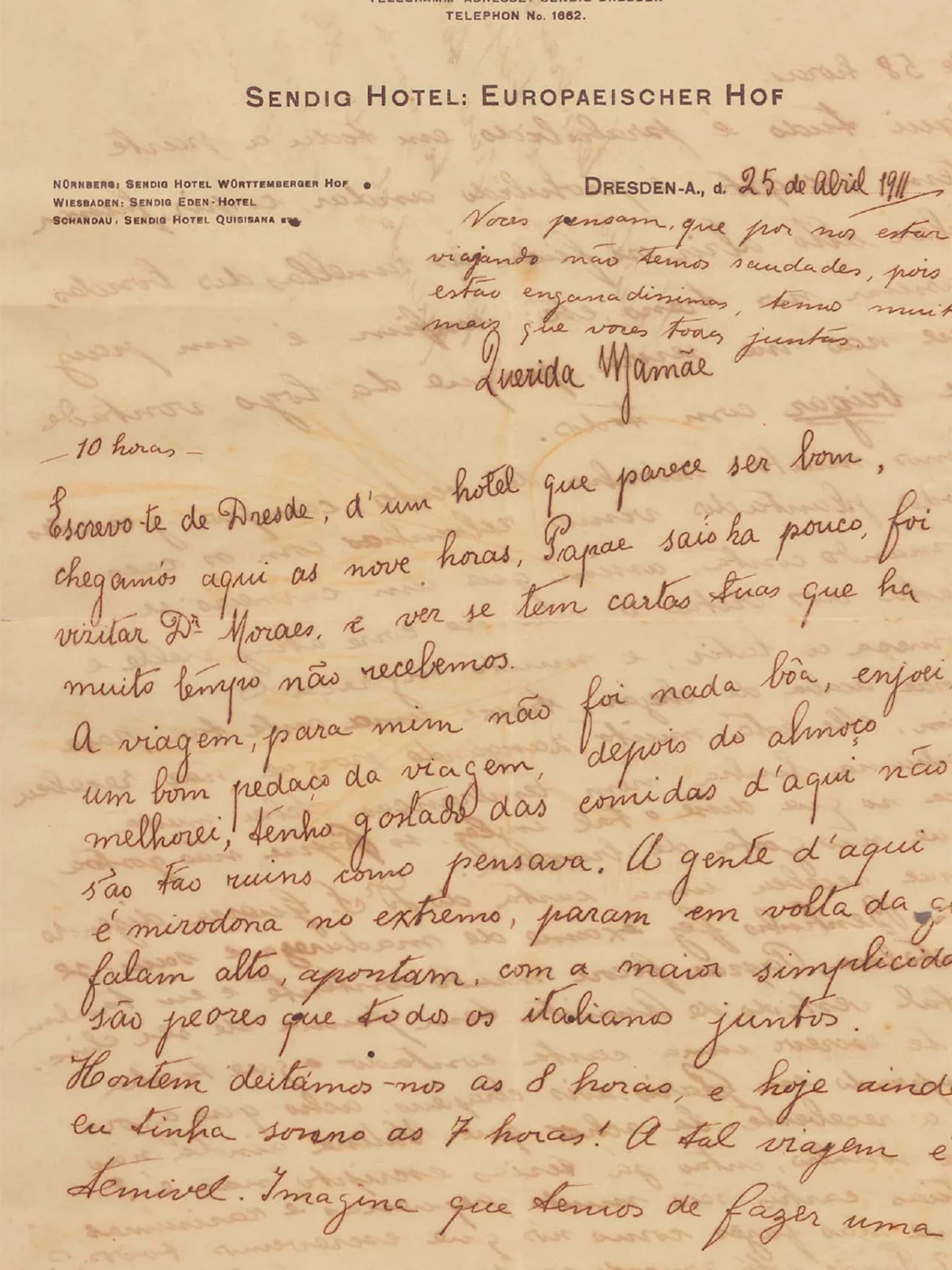 Carta manuscrita de Oswaldo para a mãe, em papel amarelado e timbrado, do Hotel Sendig Hotel, de Dresden. Escrito à mão: “25 de abril de 1911. Vocês pensam que por nos estar viajando não temos saudades, pois estão enganadíssimos, temos muito mais que vocês todos juntos. Querida mamãe.” Para conhecer o conteúdo das duas páginas da carta, leia as cartas de Oswaldo e sua família.